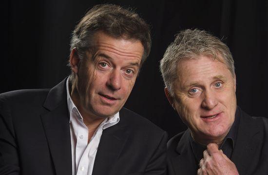 Bernd Kohlhepp & Uli Boettcher stehen in schwarzen Anzügen vor der Kamera.